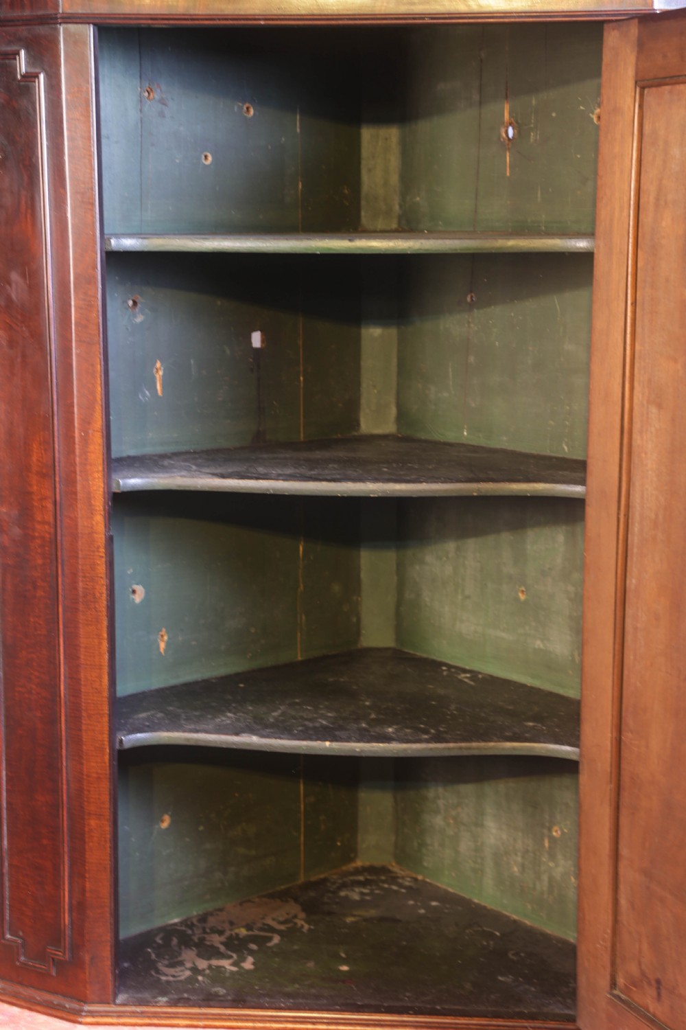 A Georgian mahogany corner cupboard featuring a swan-neck pediment with carved rosettes and a single flame mahogany panelled door. View V