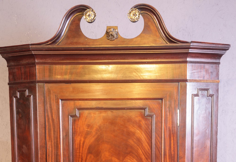 A Georgian mahogany corner cupboard featuring a swan-neck pediment with carved rosettes and a single flame mahogany panelled door. View VI