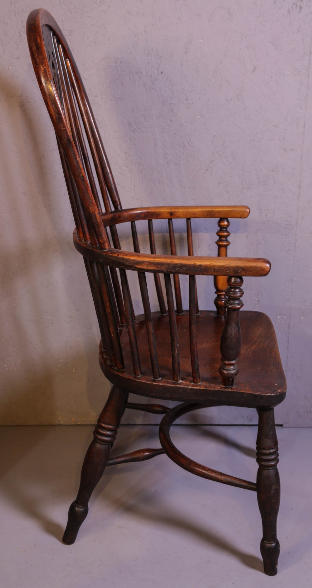 A high-back wooden Windsor armchair featuring a steam-bent hoop frame, a central pierced splat, turned legs, and a contoured elm saddle seat. View III
