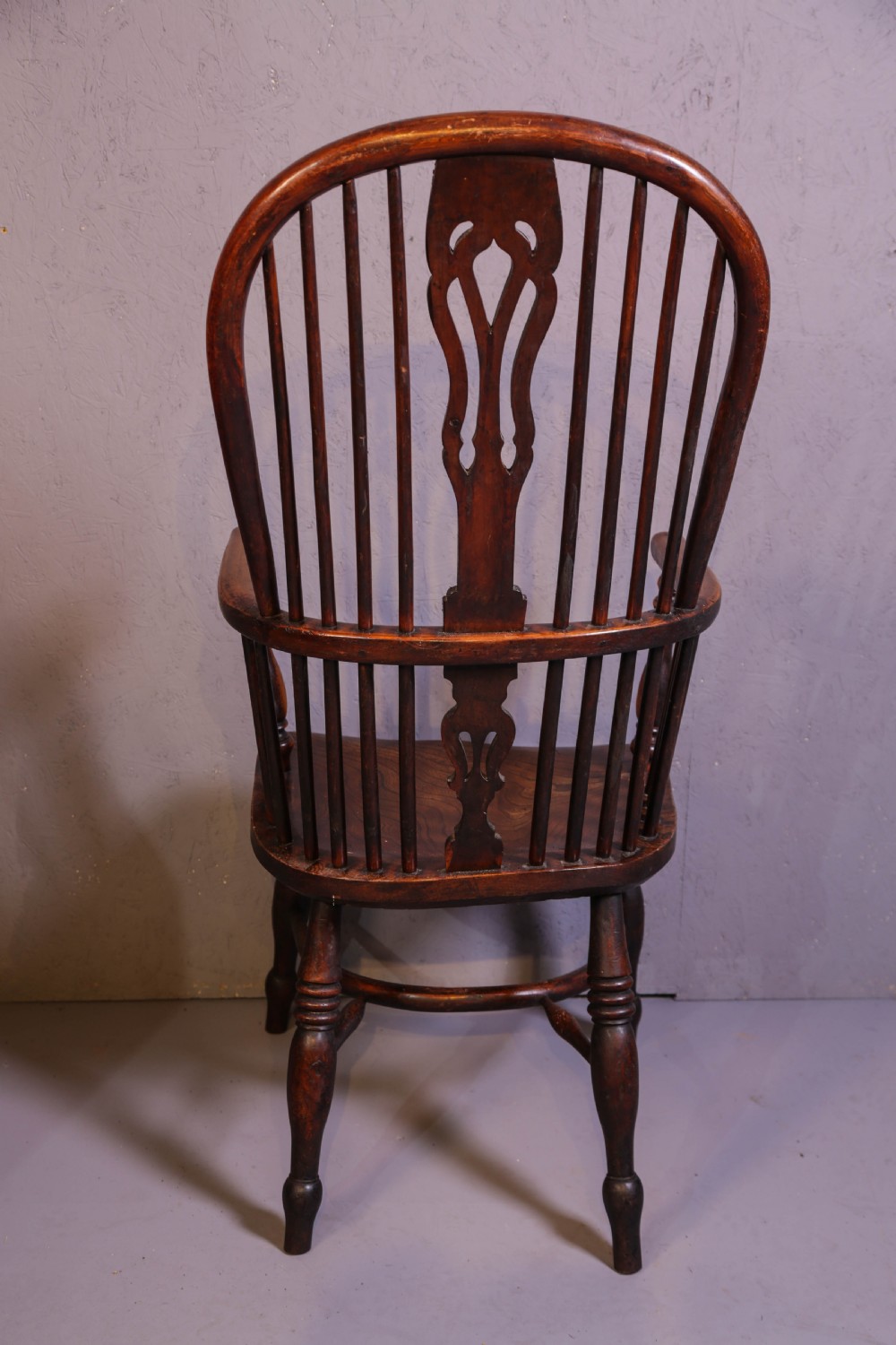 A high-back wooden Windsor armchair featuring a steam-bent hoop frame, a central pierced splat, turned legs, and a contoured elm saddle seat. View V