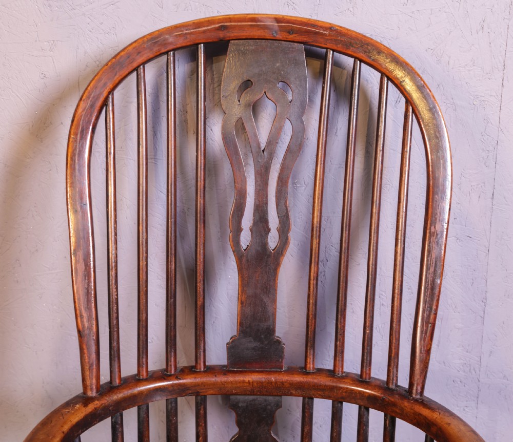 A high-back wooden Windsor armchair featuring a steam-bent hoop frame, a central pierced splat, turned legs, and a contoured elm saddle seat. View X