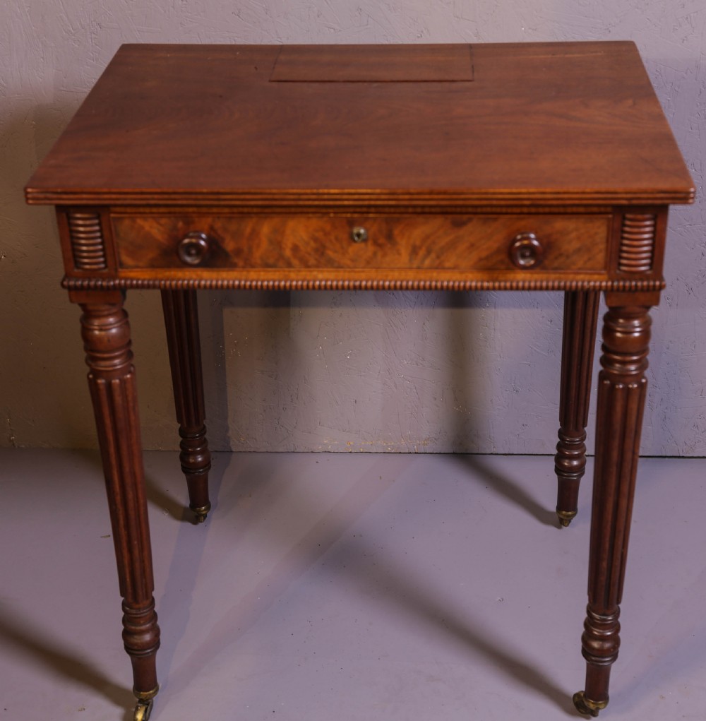 An antique mahogany library table featuring turned reeded legs with brass castors, a single frieze drawer with turned wooden handles, and a rectangular top.