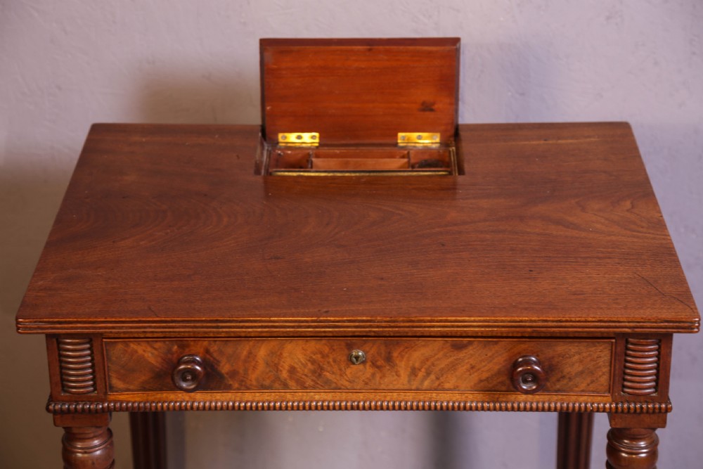 An antique mahogany library table featuring turned reeded legs with brass castors, a single frieze drawer with turned wooden handles, and a rectangular top. View III