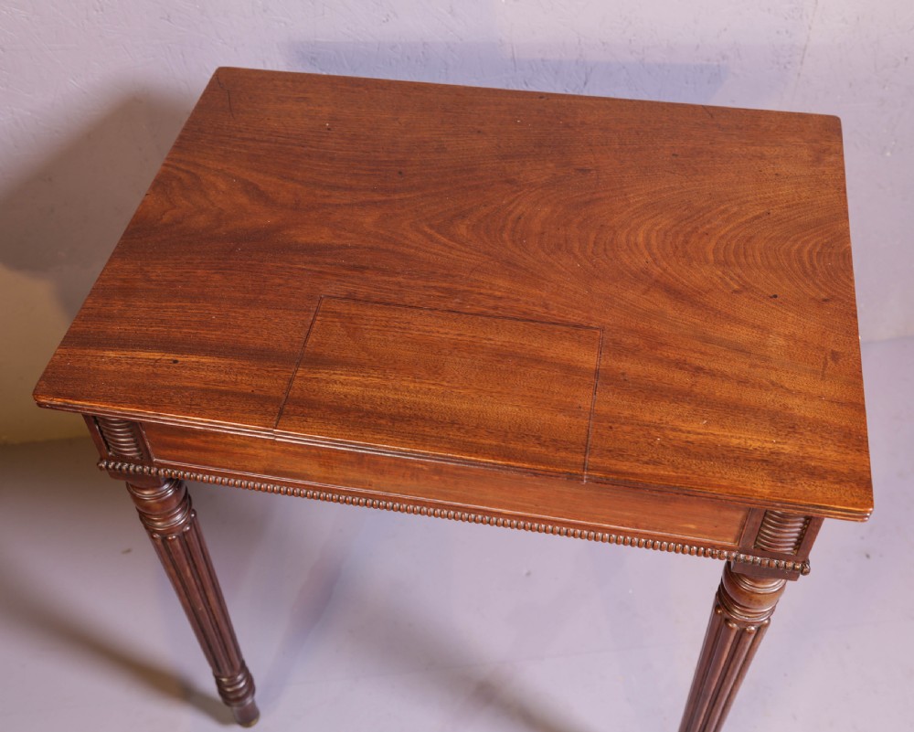 An antique mahogany library table featuring turned reeded legs with brass castors, a single frieze drawer with turned wooden handles, and a rectangular top. View IX