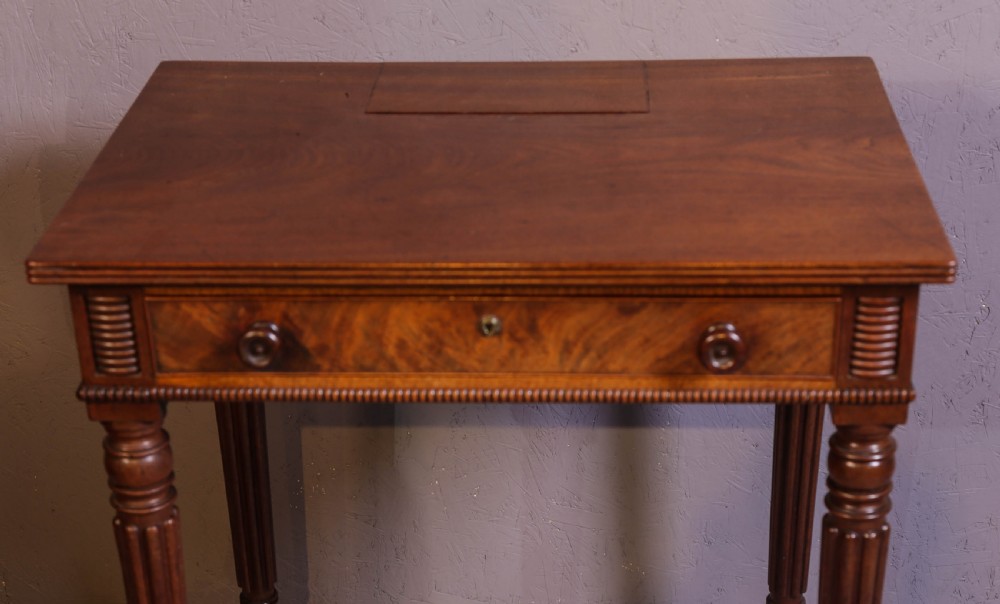 An antique mahogany library table featuring turned reeded legs with brass castors, a single frieze drawer with turned wooden handles, and a rectangular top. View X
