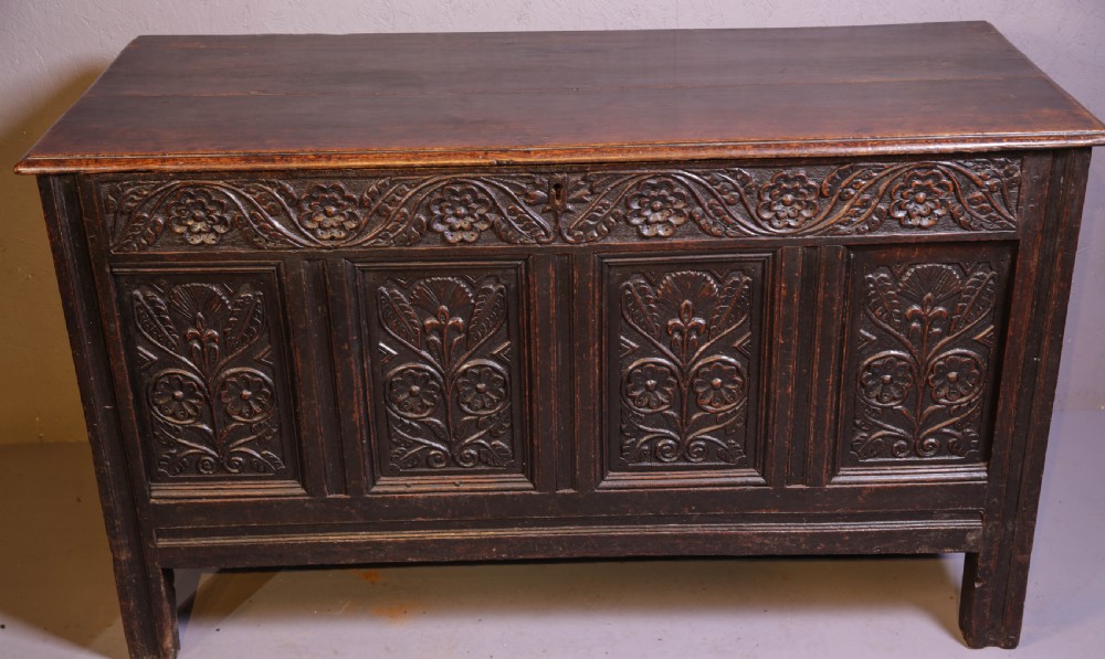 A dark brown oak coffer featuring four carved floral front panels beneath a carved lunette frieze. View VII