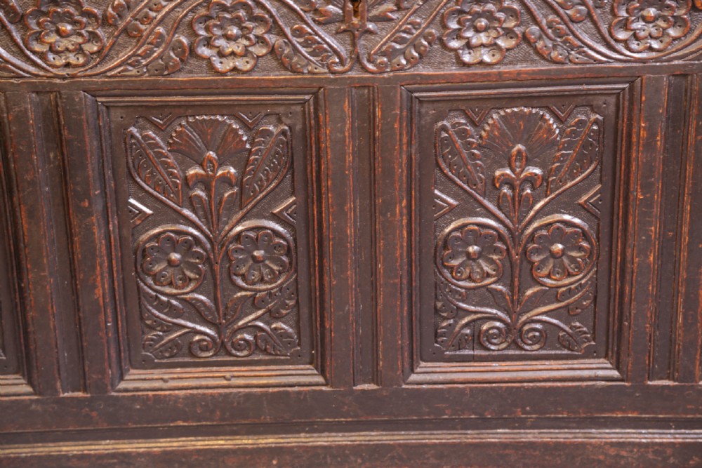 A dark brown oak coffer featuring four carved floral front panels beneath a carved lunette frieze. View VIII