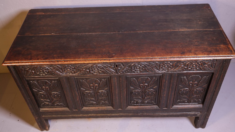A dark brown oak coffer featuring four carved floral front panels beneath a carved lunette frieze. View IX
