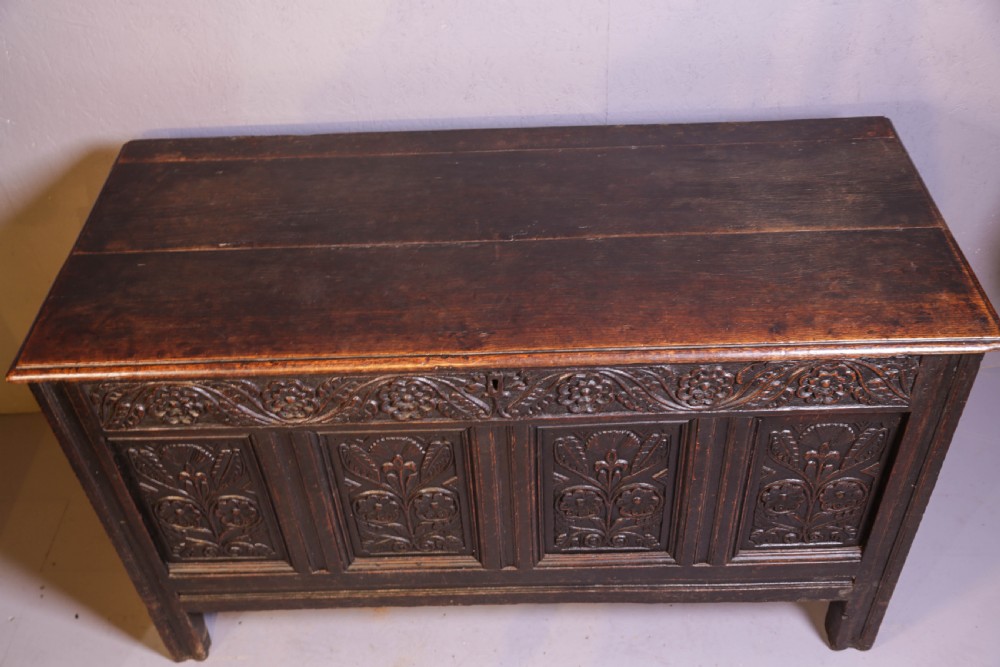 A dark brown oak coffer featuring four carved floral front panels beneath a carved lunette frieze. View X