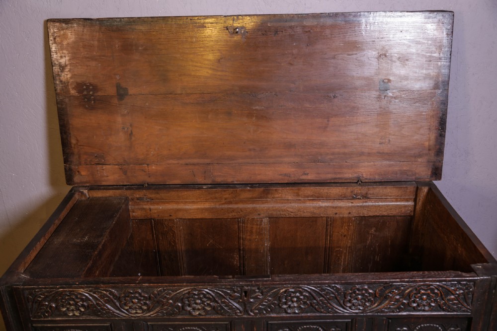 A dark brown oak coffer featuring four carved floral front panels beneath a carved lunette frieze. View XI