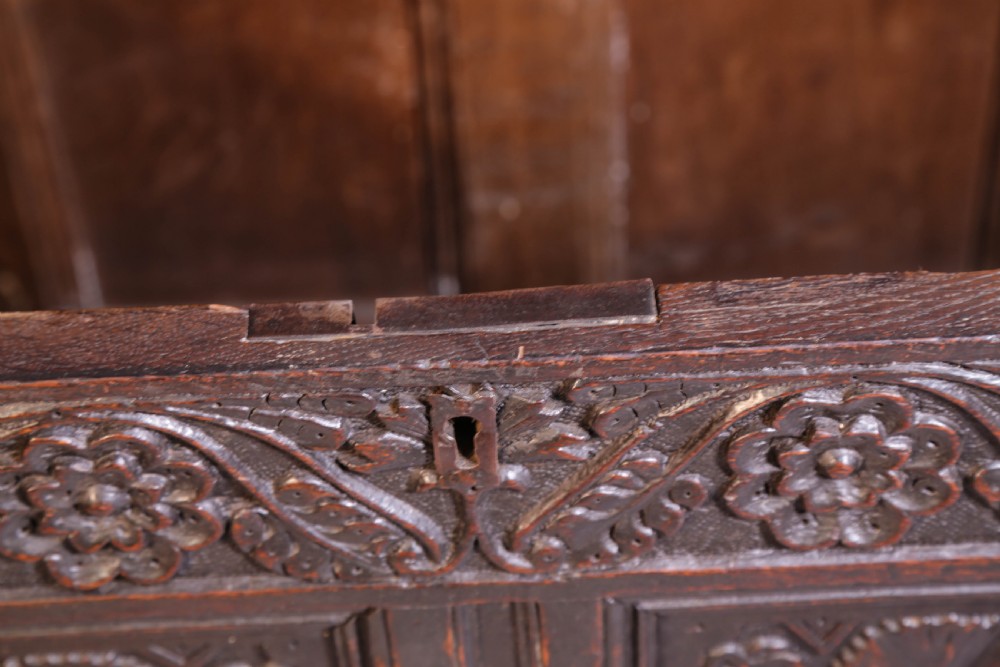 A dark brown oak coffer featuring four carved floral front panels beneath a carved lunette frieze. View XVI