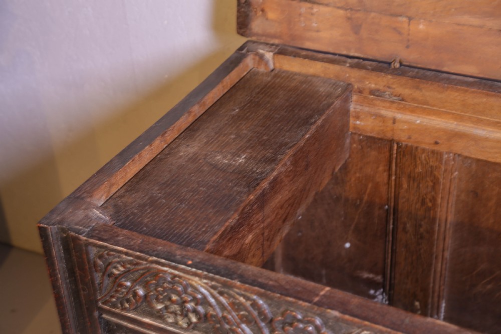 A dark brown oak coffer featuring four carved floral front panels beneath a carved lunette frieze. View XVII