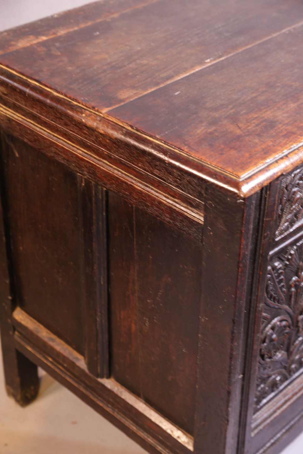 A dark brown oak coffer featuring four carved floral front panels beneath a carved lunette frieze. View XVIII