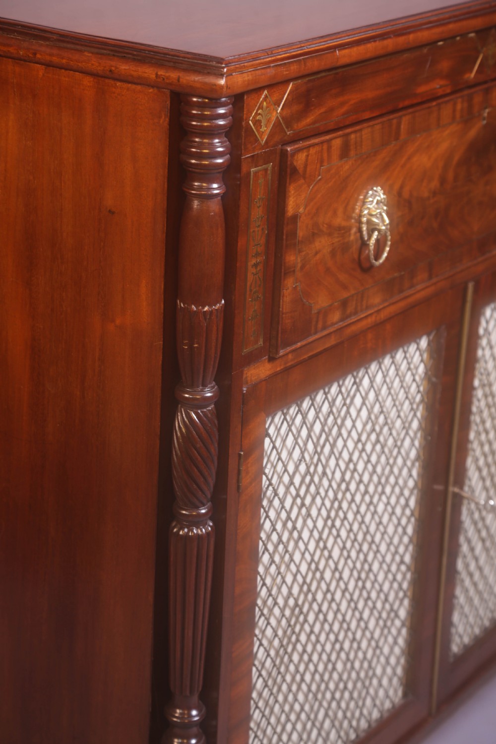 A Regency rosewood chiffonier with brass inlay, a long drawer featuring lion mask handles, and lower double doors with brass wire grilles over fabric. View III