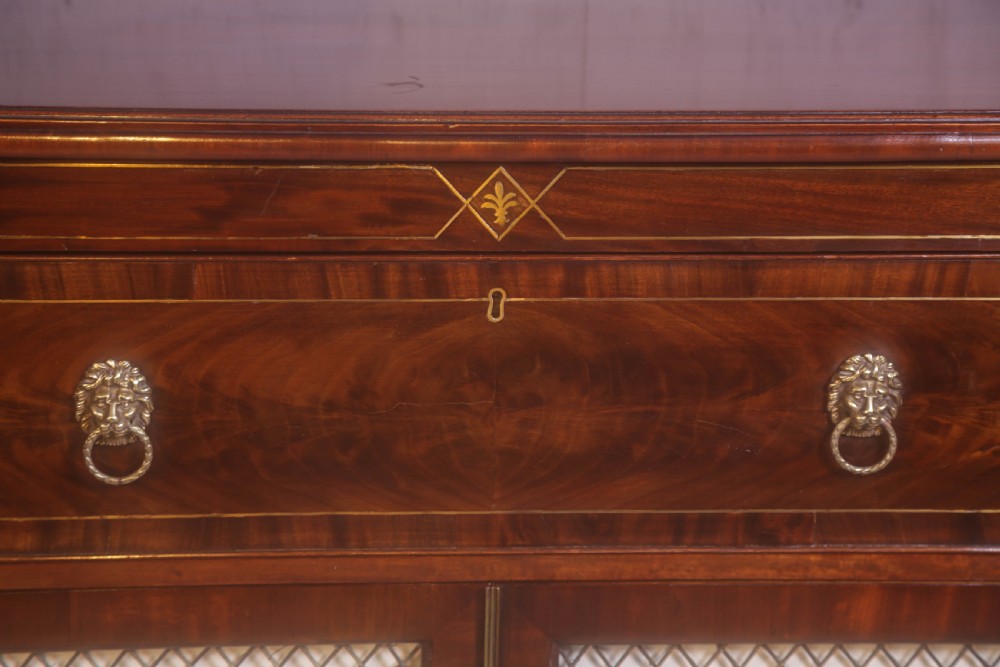 A Regency rosewood chiffonier with brass inlay, a long drawer featuring lion mask handles, and lower double doors with brass wire grilles over fabric. View XII