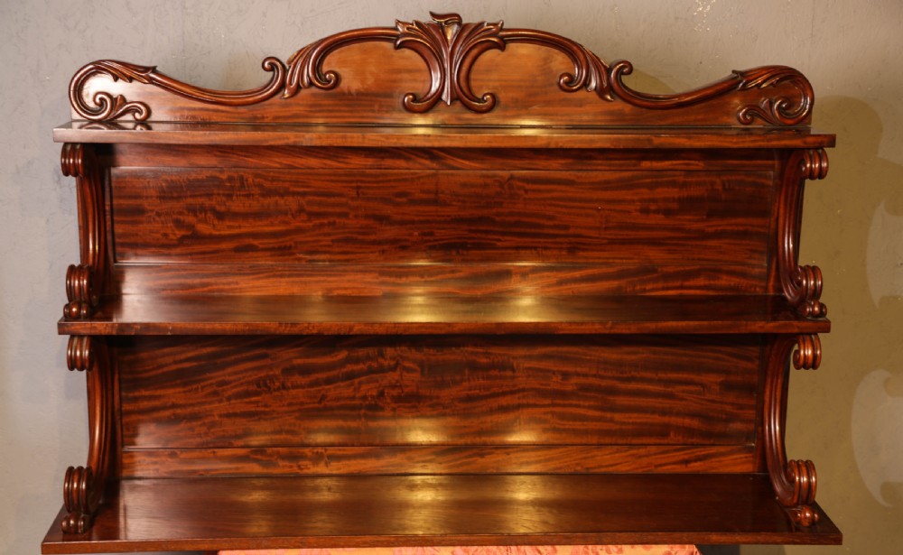 A three-tier Victorian mahogany wall shelf featuring an ornate carved cresting rail and curved side supports.