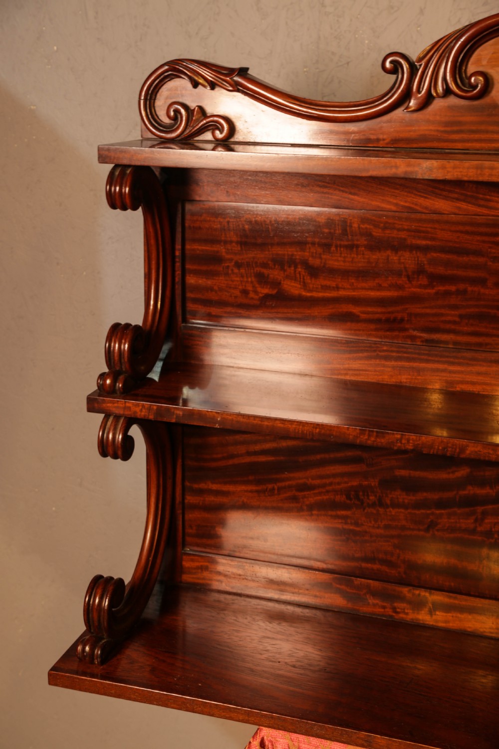 A three-tier Victorian mahogany wall shelf featuring an ornate carved cresting rail and curved side supports. View IV