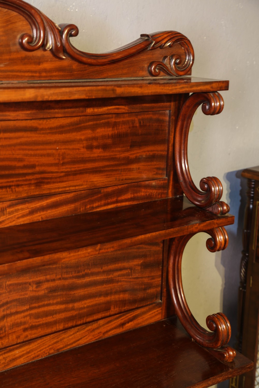 A three-tier Victorian mahogany wall shelf featuring an ornate carved cresting rail and curved side supports. View V