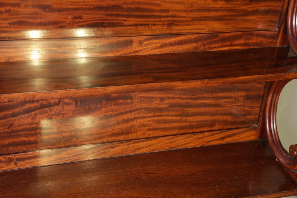 A three-tier Victorian mahogany wall shelf featuring an ornate carved cresting rail and curved side supports. View VI