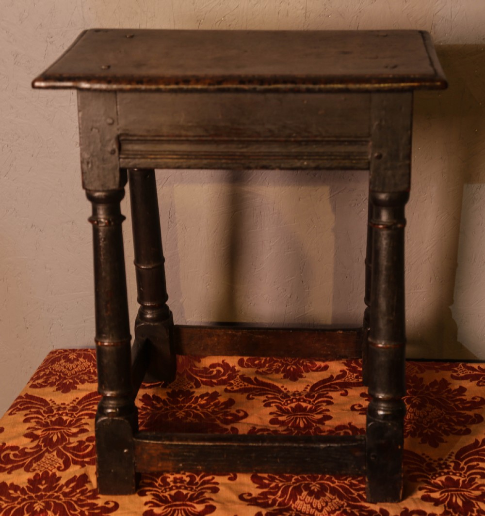 A seventeenth-century dark oak joint stool featuring turned legs, lower perimeter stretchers, and a flat top secured with wooden pegs. View II