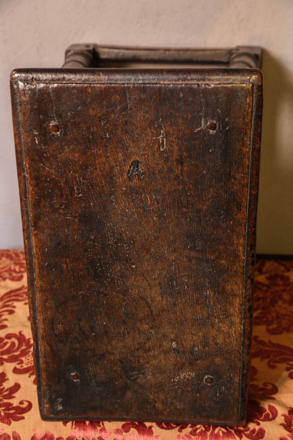 A seventeenth-century dark oak joint stool featuring turned legs, lower perimeter stretchers, and a flat top secured with wooden pegs. View VII