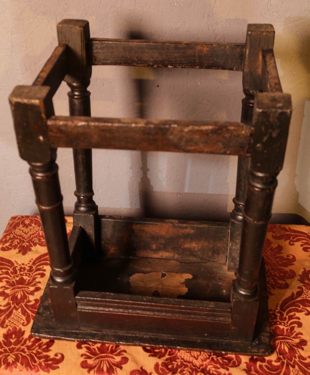 A seventeenth-century dark oak joint stool featuring turned legs, lower perimeter stretchers, and a flat top secured with wooden pegs. View X