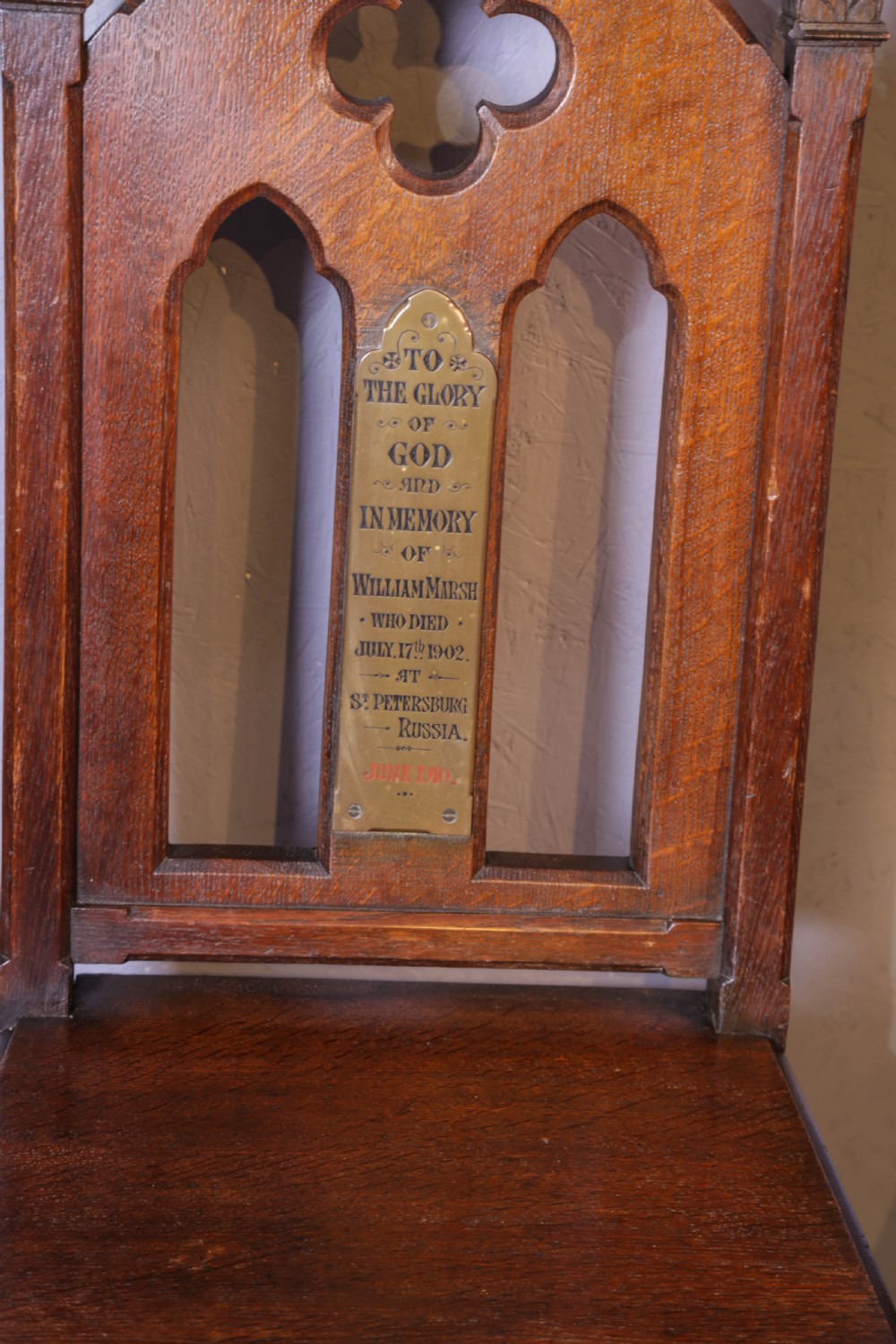 A pair of dark oak Gothic Revival church chairs featuring pointed arch backs, carved trefoil tracery, decorative corner finials, and central brass memorial plaques. View IV