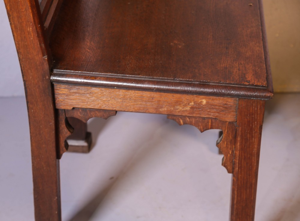 A pair of dark oak Gothic Revival church chairs featuring pointed arch backs, carved trefoil tracery, decorative corner finials, and central brass memorial plaques. View VII