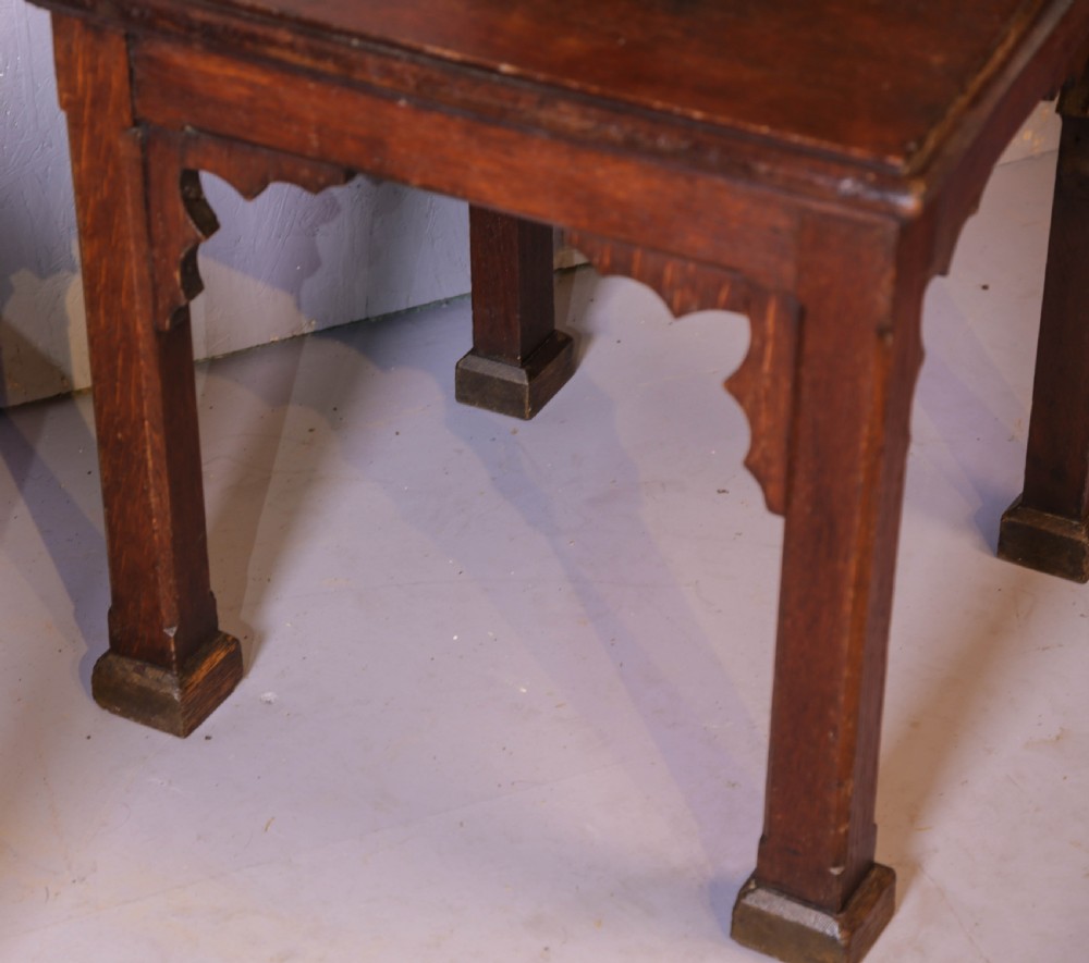 A pair of dark oak Gothic Revival church chairs featuring pointed arch backs, carved trefoil tracery, decorative corner finials, and central brass memorial plaques. View IX