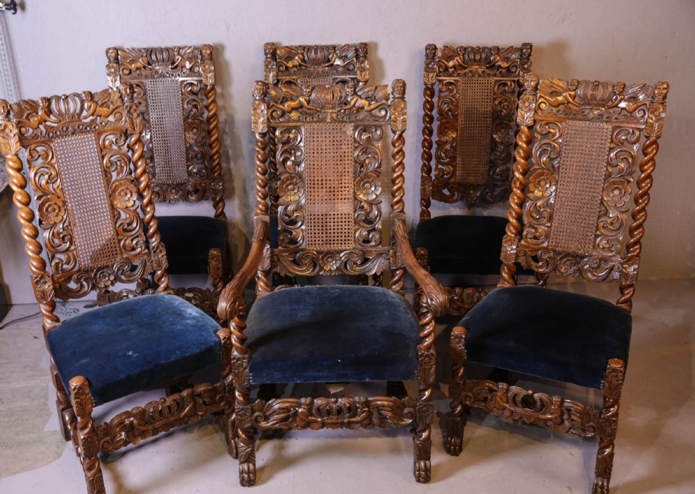 Set of six high-backed Carolean style walnut dining chairs featuring intricate scroll and crown carvings, barley twist pillars, cane back panels, and blue velvet upholstered seats. View II