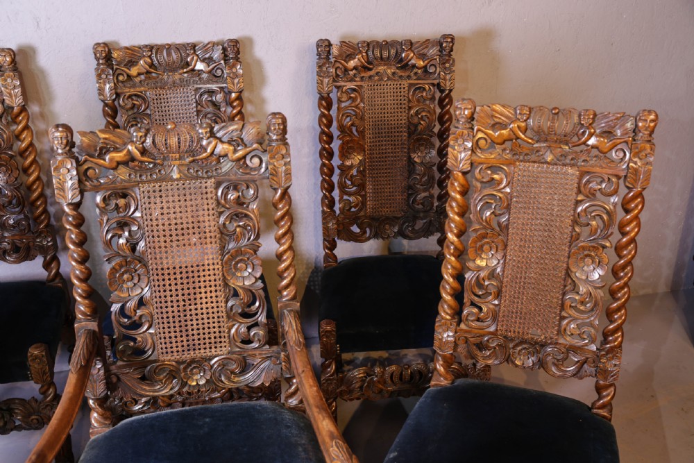Set of six high-backed Carolean style walnut dining chairs featuring intricate scroll and crown carvings, barley twist pillars, cane back panels, and blue velvet upholstered seats. View III