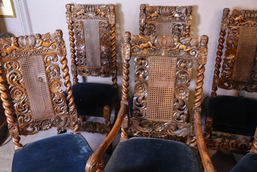Set of six high-backed Carolean style walnut dining chairs featuring intricate scroll and crown carvings, barley twist pillars, cane back panels, and blue velvet upholstered seats. View IV
