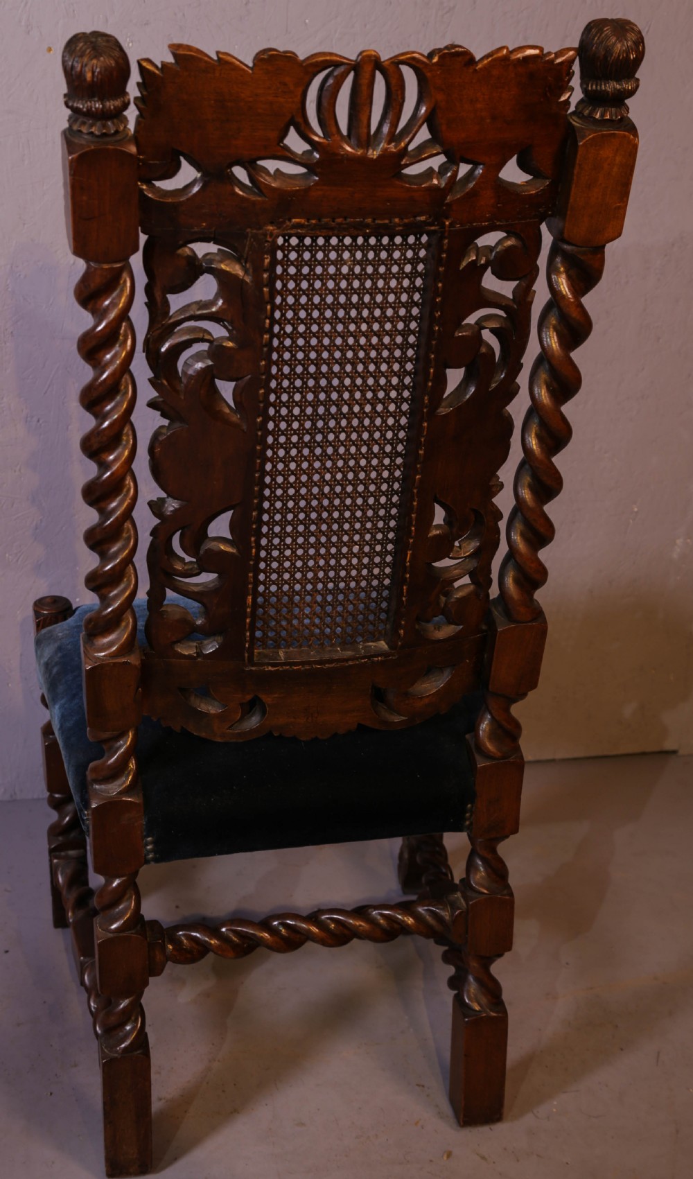 Set of six high-backed Carolean style walnut dining chairs featuring intricate scroll and crown carvings, barley twist pillars, cane back panels, and blue velvet upholstered seats. View XI