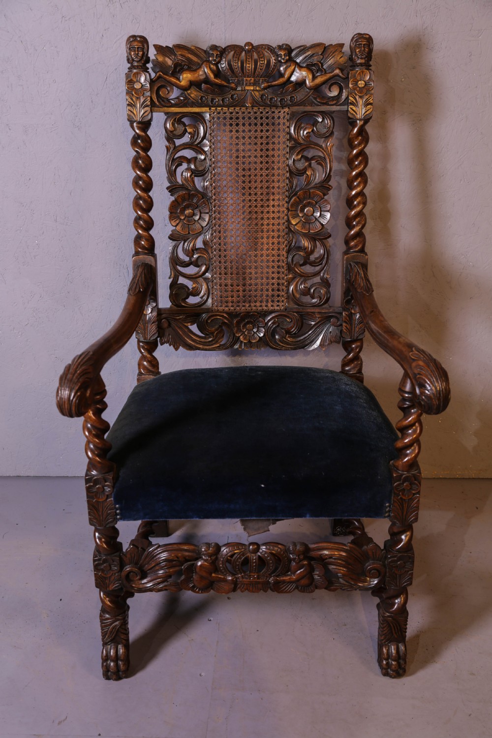 Set of six high-backed Carolean style walnut dining chairs featuring intricate scroll and crown carvings, barley twist pillars, cane back panels, and blue velvet upholstered seats. View XII