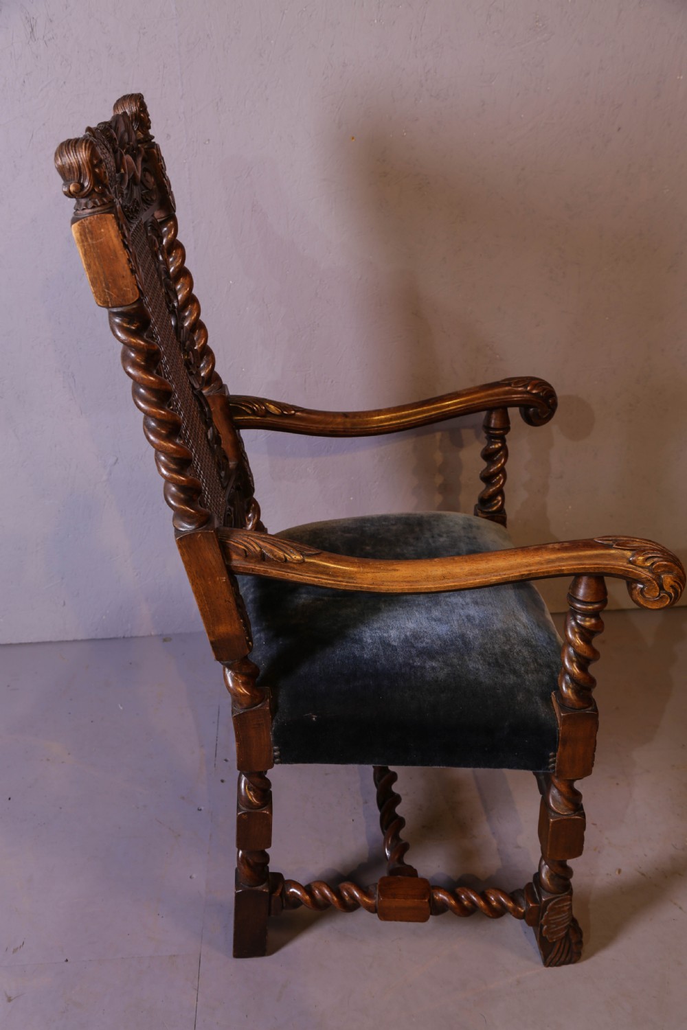 Set of six high-backed Carolean style walnut dining chairs featuring intricate scroll and crown carvings, barley twist pillars, cane back panels, and blue velvet upholstered seats. View XIV