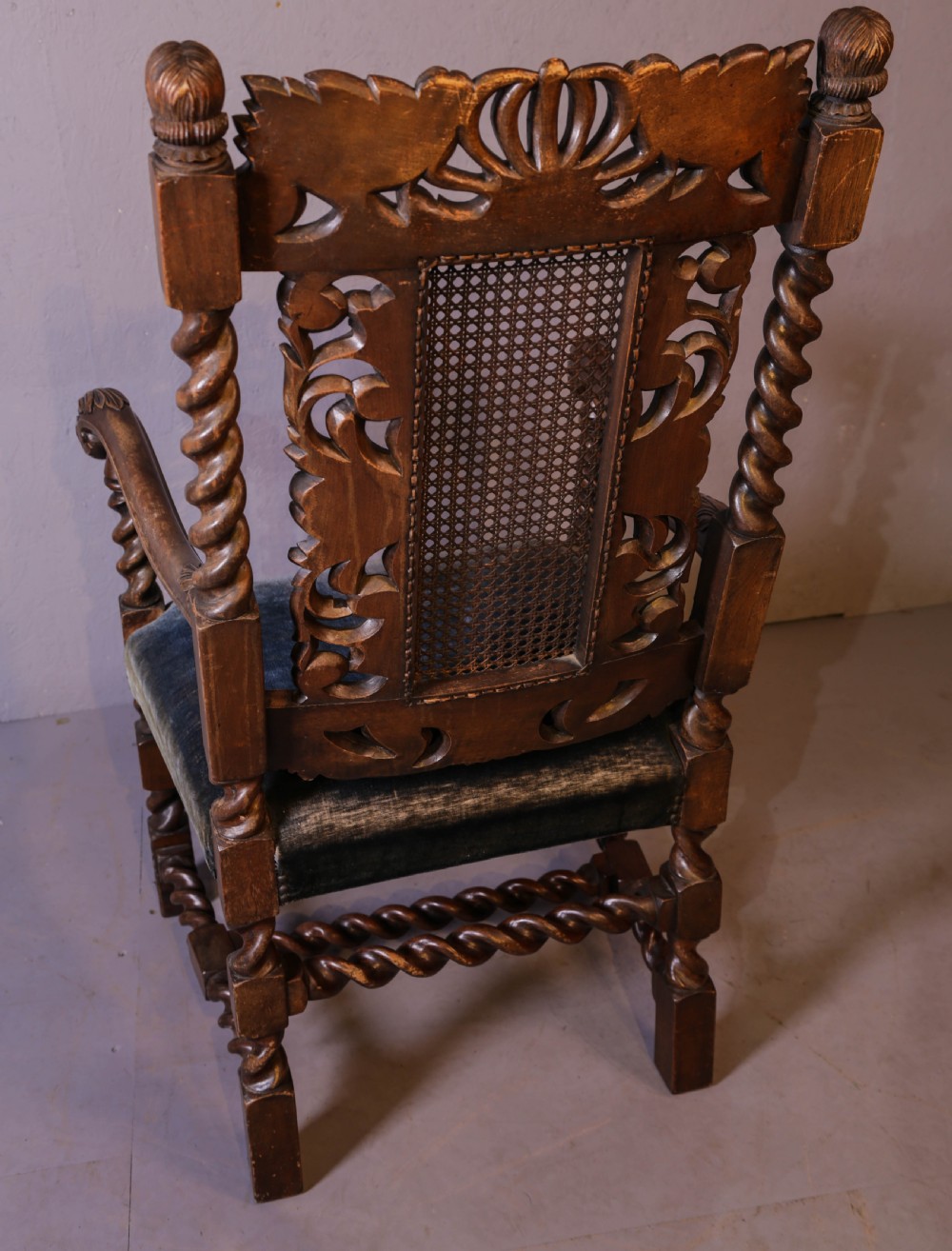Set of six high-backed Carolean style walnut dining chairs featuring intricate scroll and crown carvings, barley twist pillars, cane back panels, and blue velvet upholstered seats. View XV