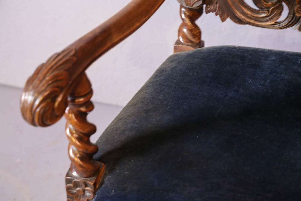 Set of six high-backed Carolean style walnut dining chairs featuring intricate scroll and crown carvings, barley twist pillars, cane back panels, and blue velvet upholstered seats. View XX