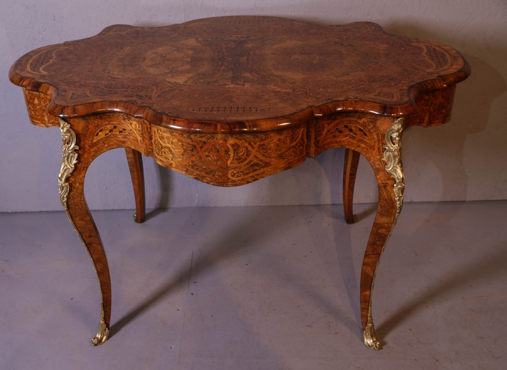 A French Rococo Revival centre table featuring burr walnut marquetry, a serpentine top, cabriole legs, and ornate gilt-bronze mounts. View II