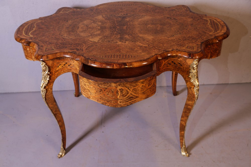 A French Rococo Revival centre table featuring burr walnut marquetry, a serpentine top, cabriole legs, and ornate gilt-bronze mounts. View III
