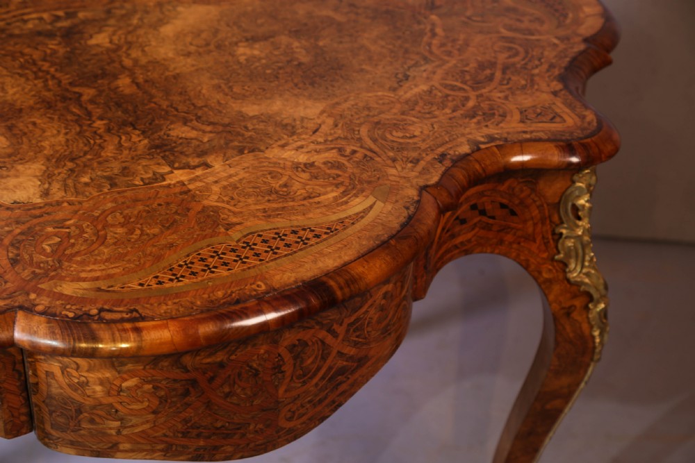 A French Rococo Revival centre table featuring burr walnut marquetry, a serpentine top, cabriole legs, and ornate gilt-bronze mounts. View VII