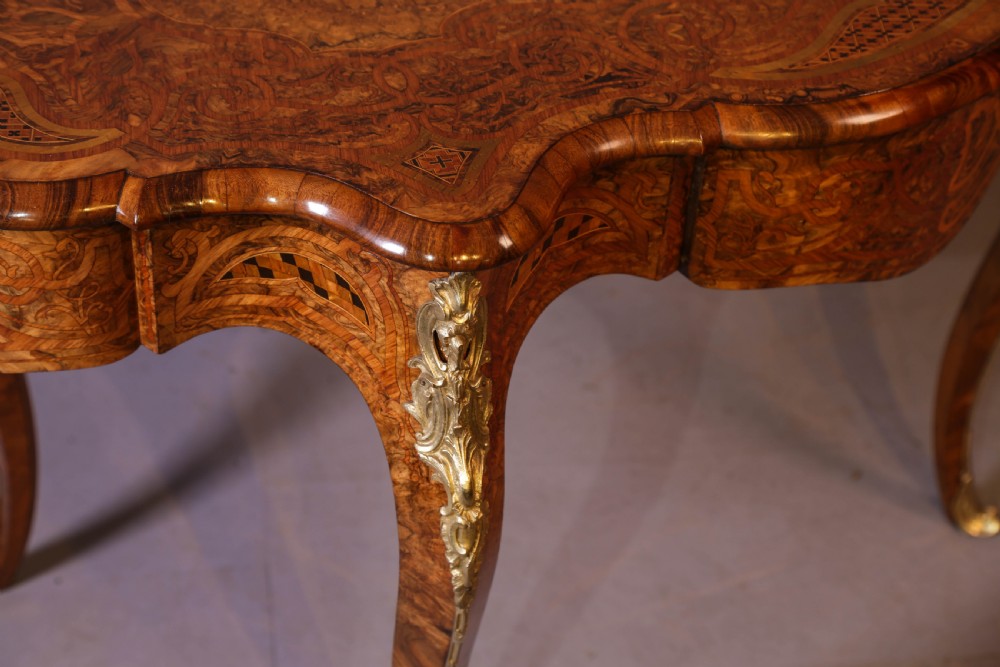 A French Rococo Revival centre table featuring burr walnut marquetry, a serpentine top, cabriole legs, and ornate gilt-bronze mounts. View IX