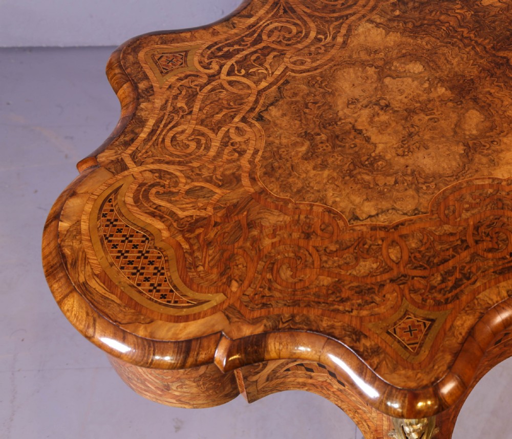 A French Rococo Revival centre table featuring burr walnut marquetry, a serpentine top, cabriole legs, and ornate gilt-bronze mounts. View XI