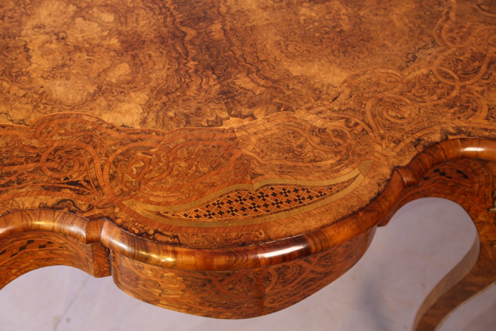A French Rococo Revival centre table featuring burr walnut marquetry, a serpentine top, cabriole legs, and ornate gilt-bronze mounts. View XIII