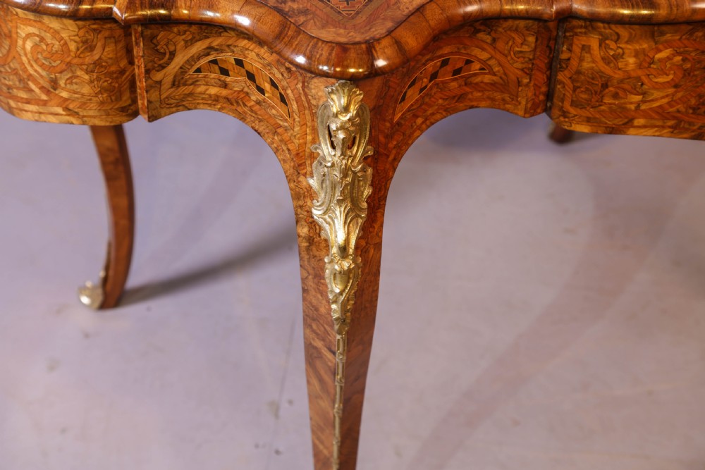 A French Rococo Revival centre table featuring burr walnut marquetry, a serpentine top, cabriole legs, and ornate gilt-bronze mounts. View XIV