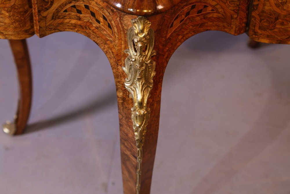 A French Rococo Revival centre table featuring burr walnut marquetry, a serpentine top, cabriole legs, and ornate gilt-bronze mounts. View XVI