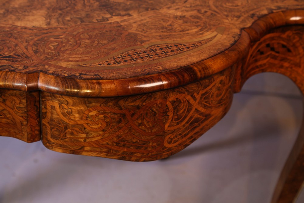 A French Rococo Revival centre table featuring burr walnut marquetry, a serpentine top, cabriole legs, and ornate gilt-bronze mounts. View XVII