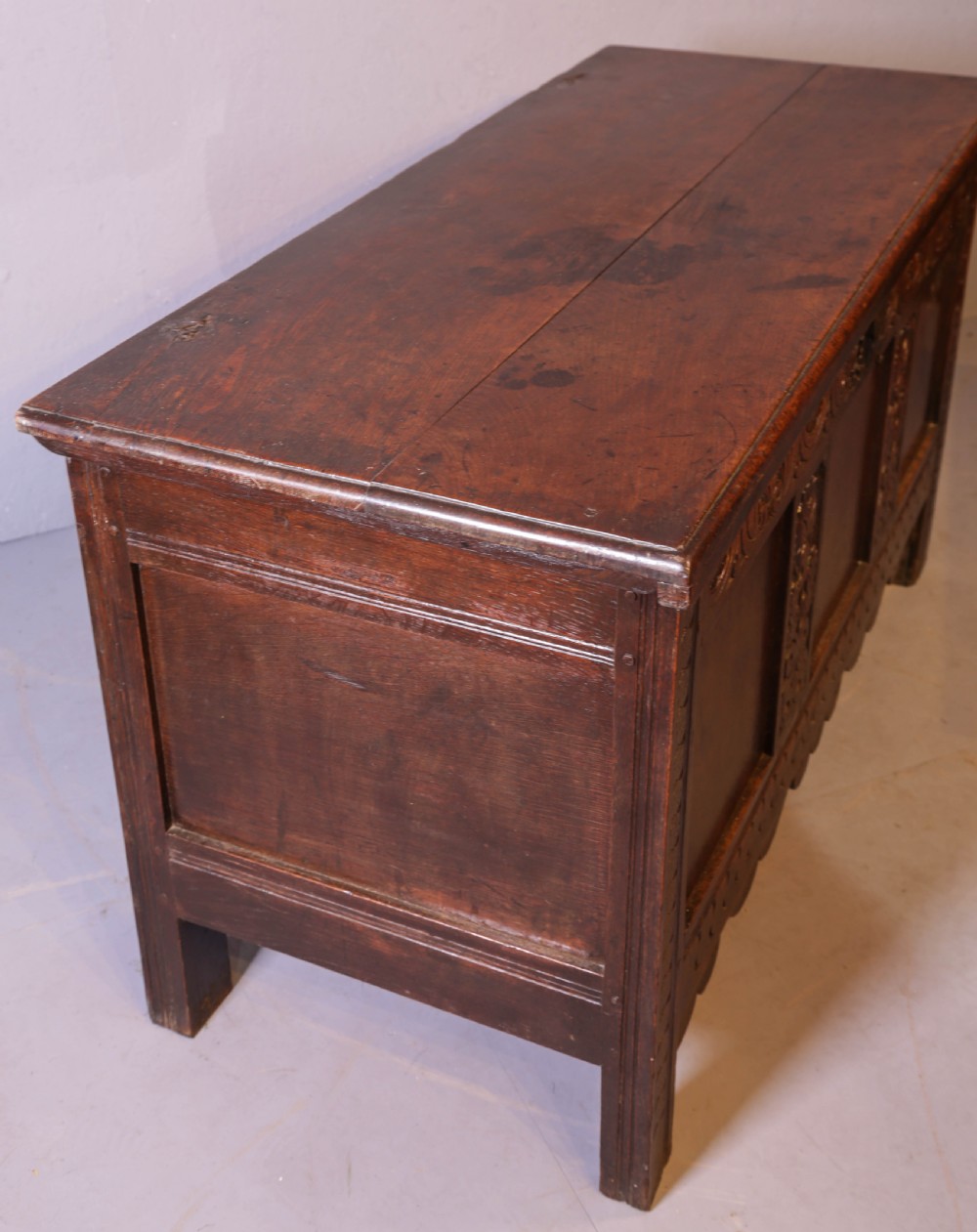 A 17th century carved oak coffer featuring a three-panel front with hand-carved leaf motifs, lunette top frieze, and iron lock plate. View III