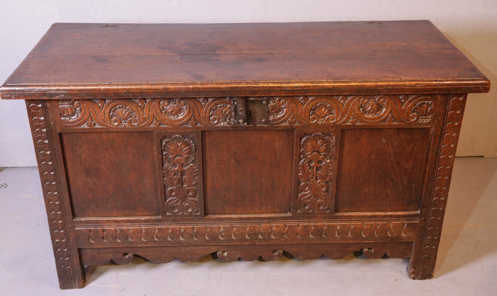 A 17th century carved oak coffer featuring a three-panel front with hand-carved leaf motifs, lunette top frieze, and iron lock plate. View IV
