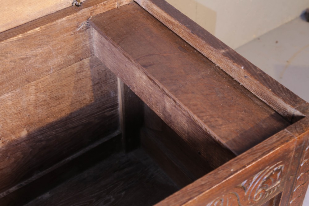 A 17th century carved oak coffer featuring a three-panel front with hand-carved leaf motifs, lunette top frieze, and iron lock plate. View VI