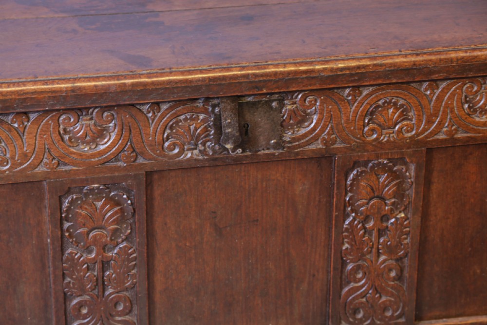 A 17th century carved oak coffer featuring a three-panel front with hand-carved leaf motifs, lunette top frieze, and iron lock plate. View VII